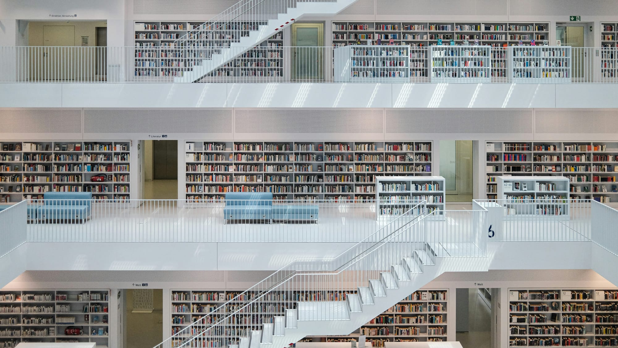 Modern minimalist white library with blue seating, representing the deep research and scholarship pipeline for Mandarin Unpeeled fellows