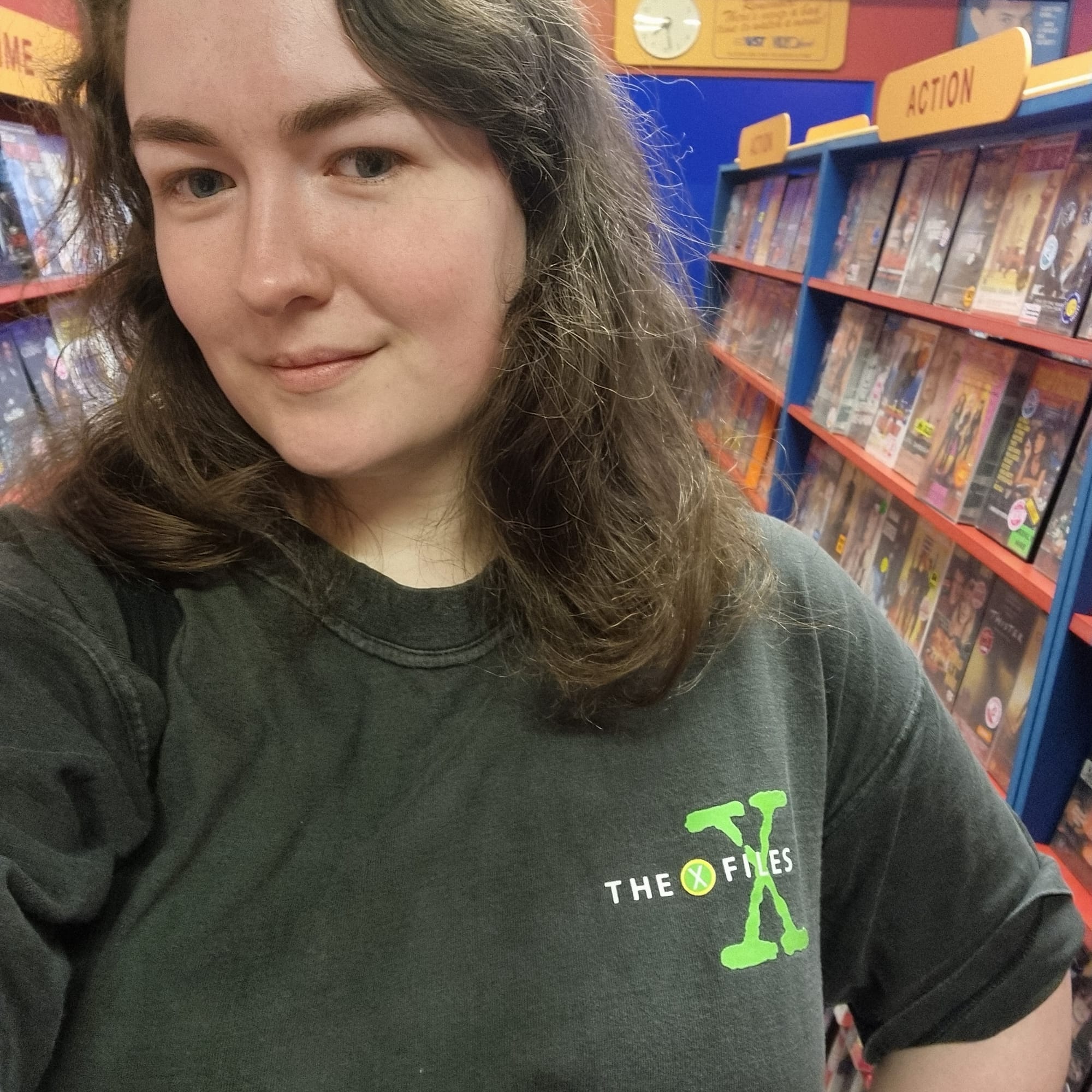 Me wearing a vintage X Files T-shirt inside a fake video rental store.