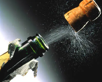 Champagne bottle cork popping with bubbles and celebration