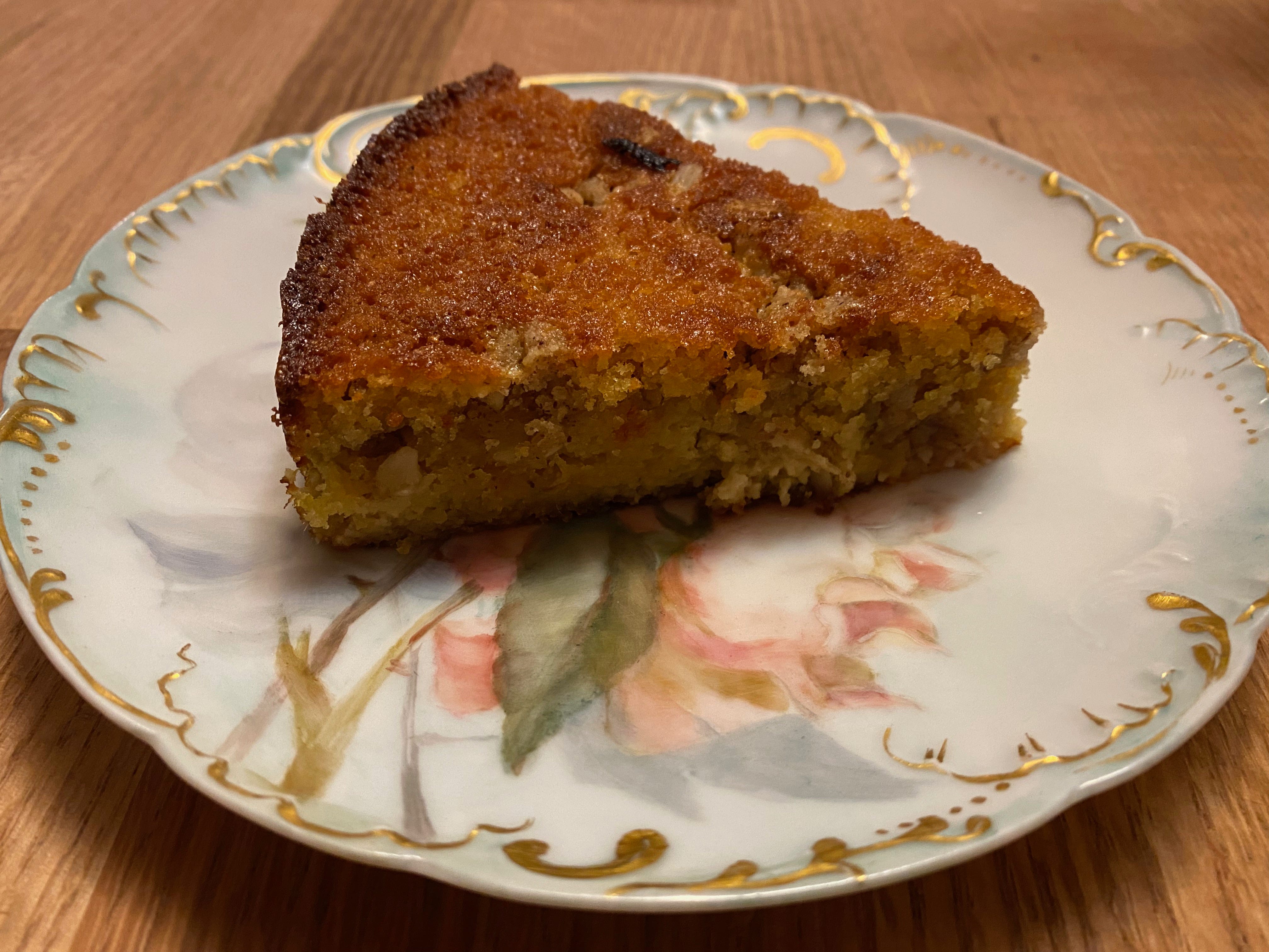 A slice of golden-crusted rhubarb cake on a ceramic plate painted with flowers.