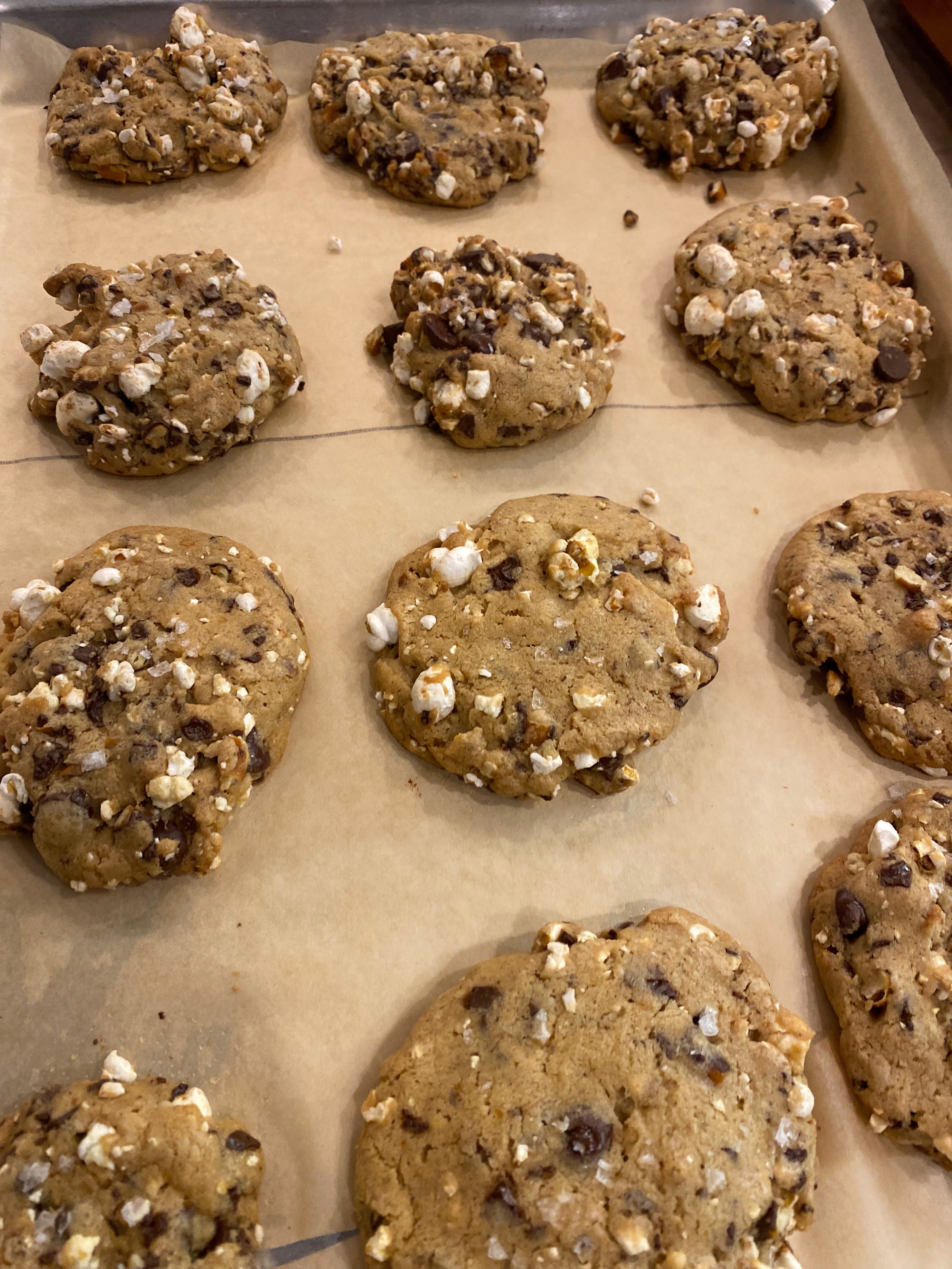 A tray of chunky chocolate chip cookies full of bits of popcorn and chocolate chunks.
