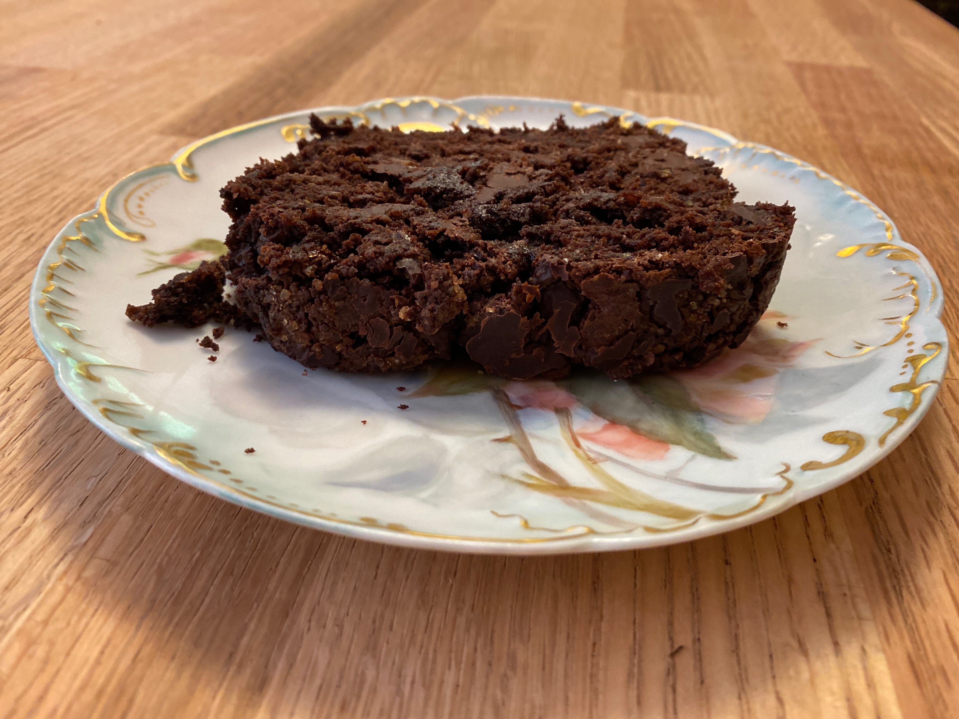A slice of chocolate zucchini cake on a small china plate.