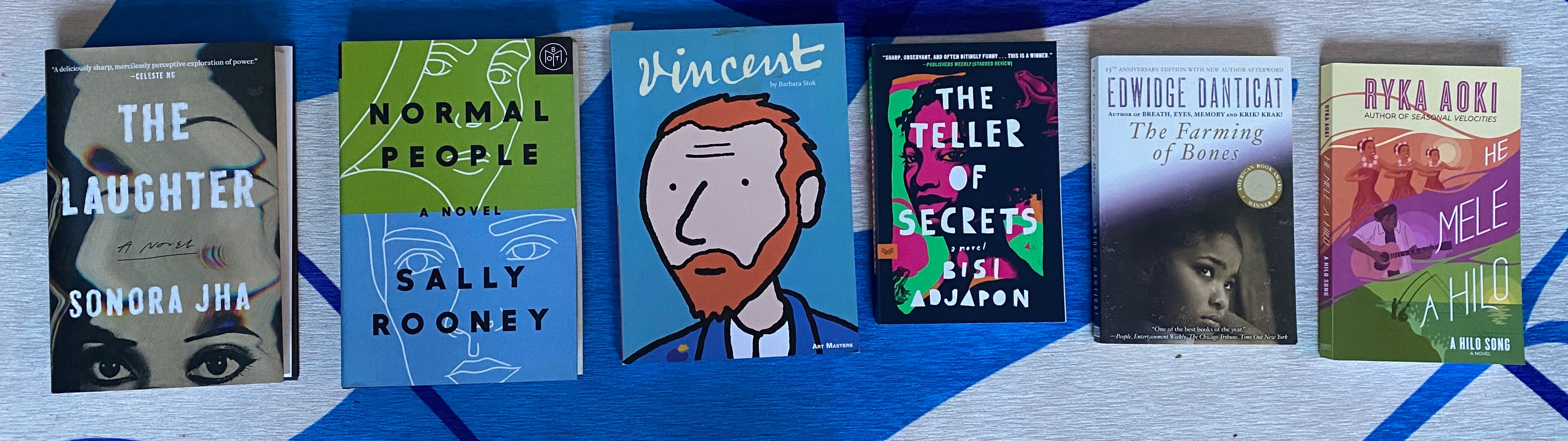 The listed books spread out in a row on a blue and white rug.