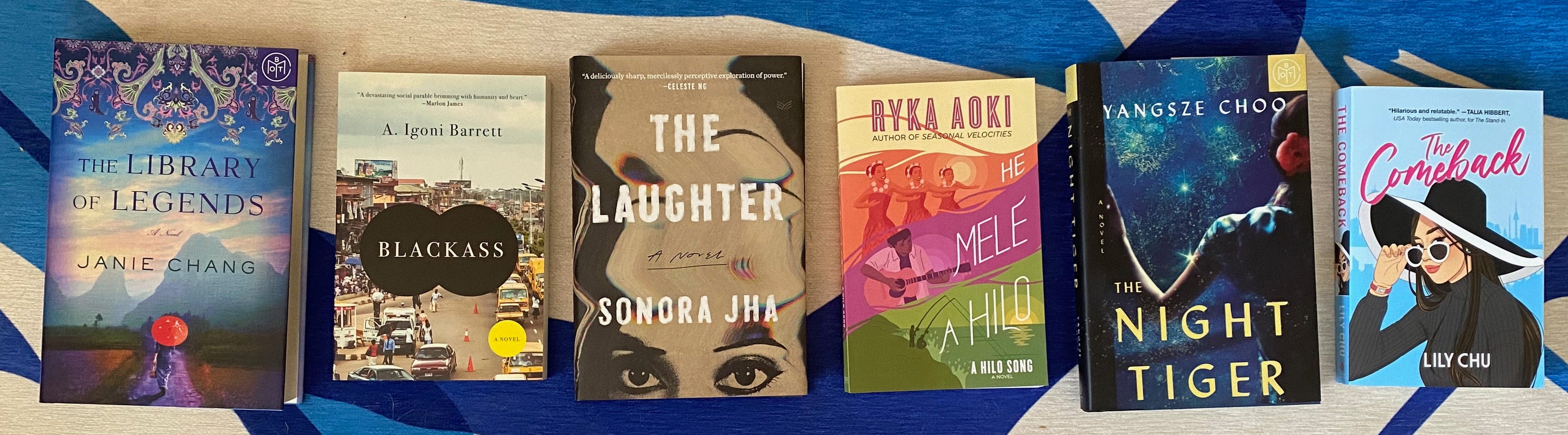 The listed books laid out in a row on a blue and white rug.