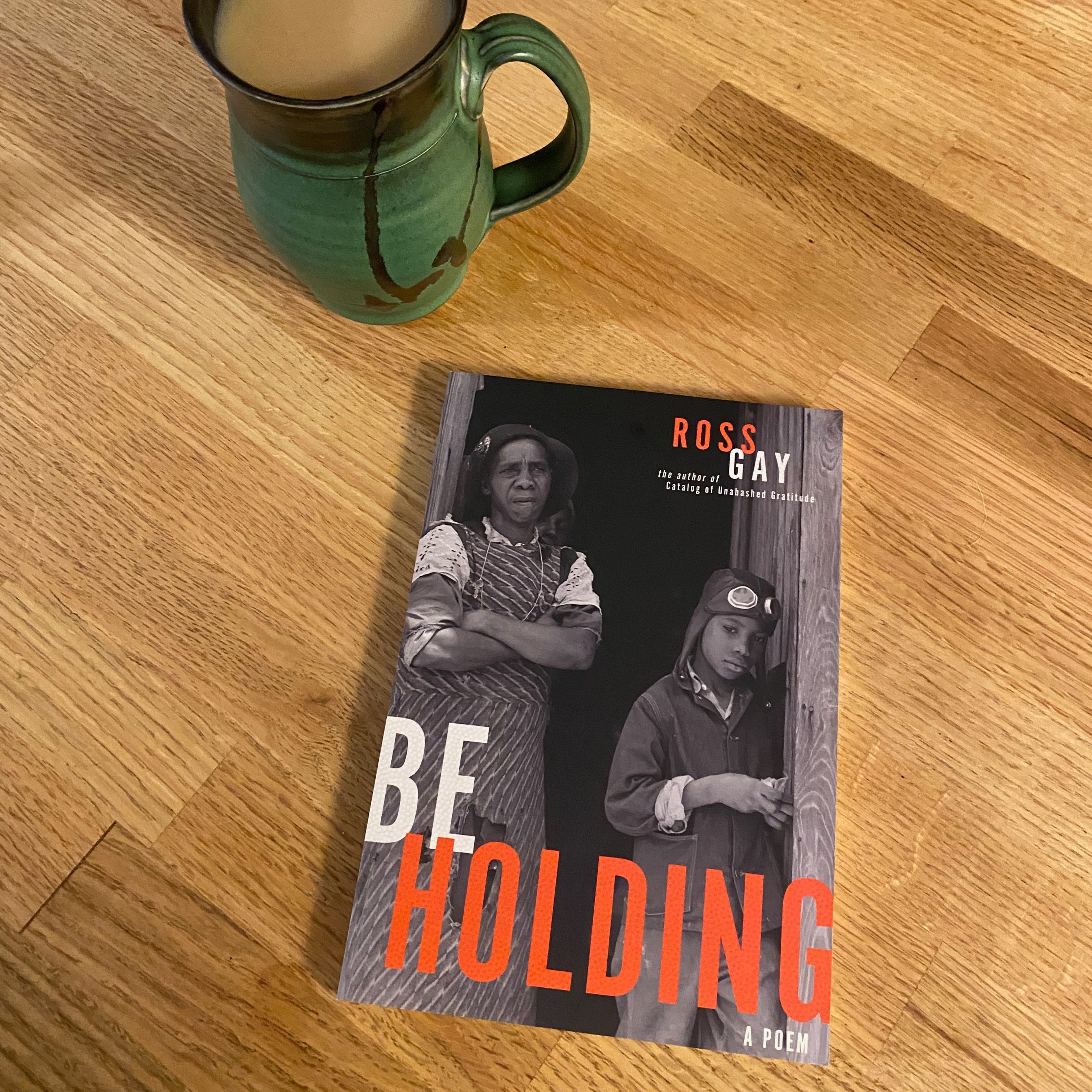 This book sits on a wooden table next to a green ceramic mug of tea.