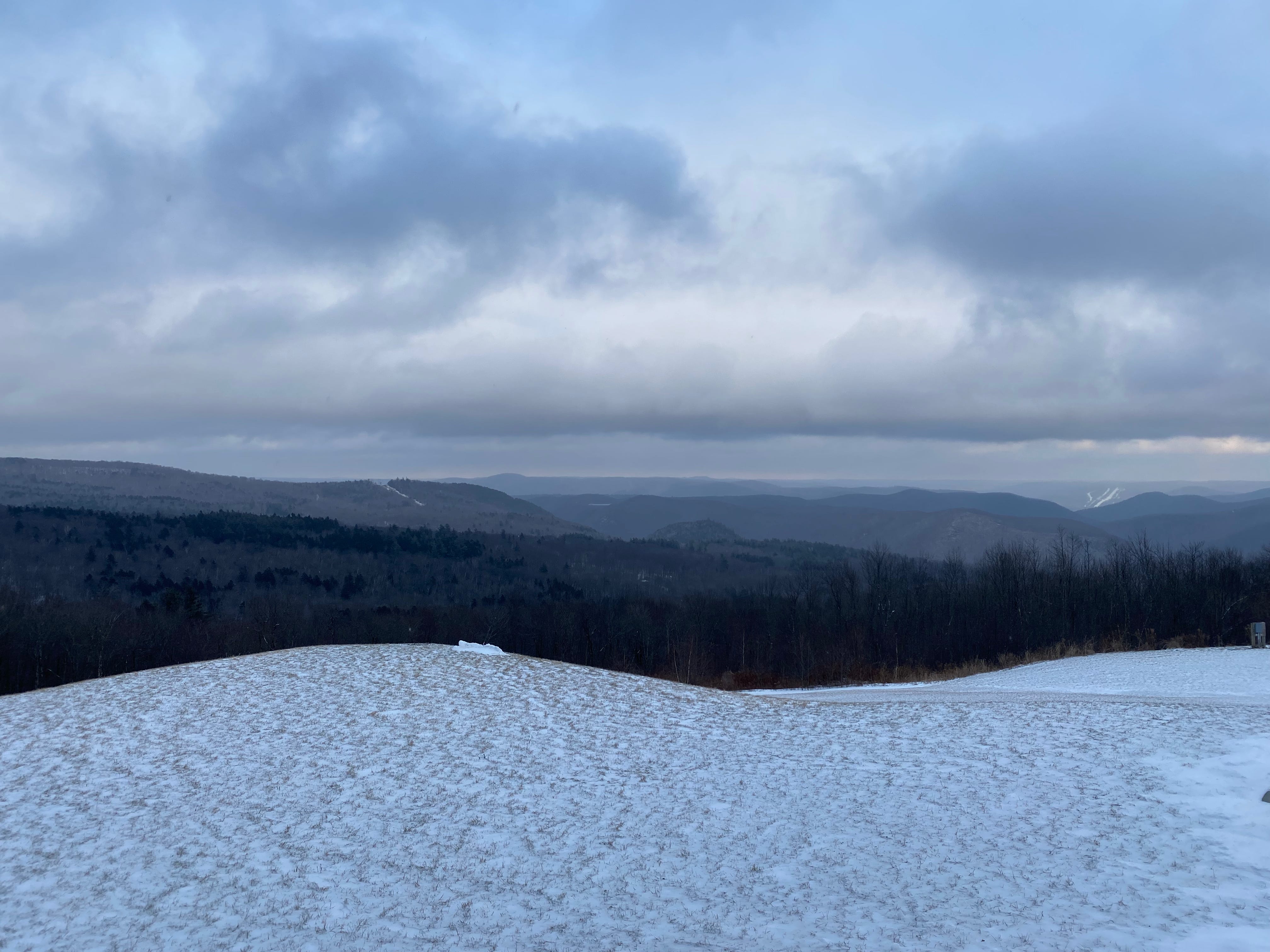 A vista of snowy mountains on a dark, cloudy afternoon.