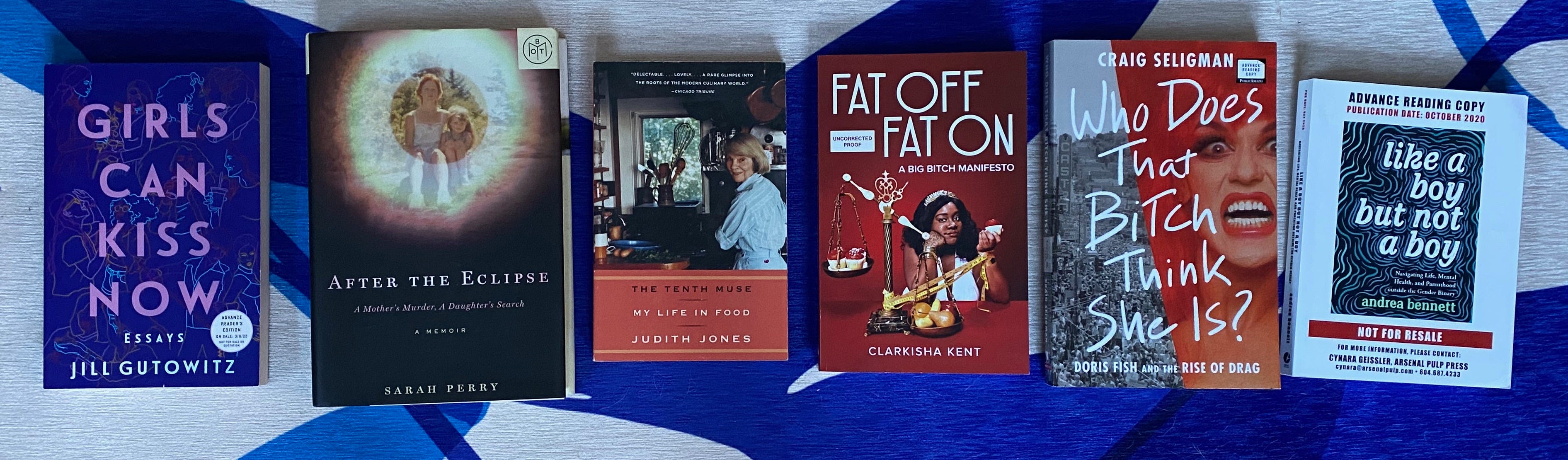 The listed books spread out in a row on a blue and white rug.