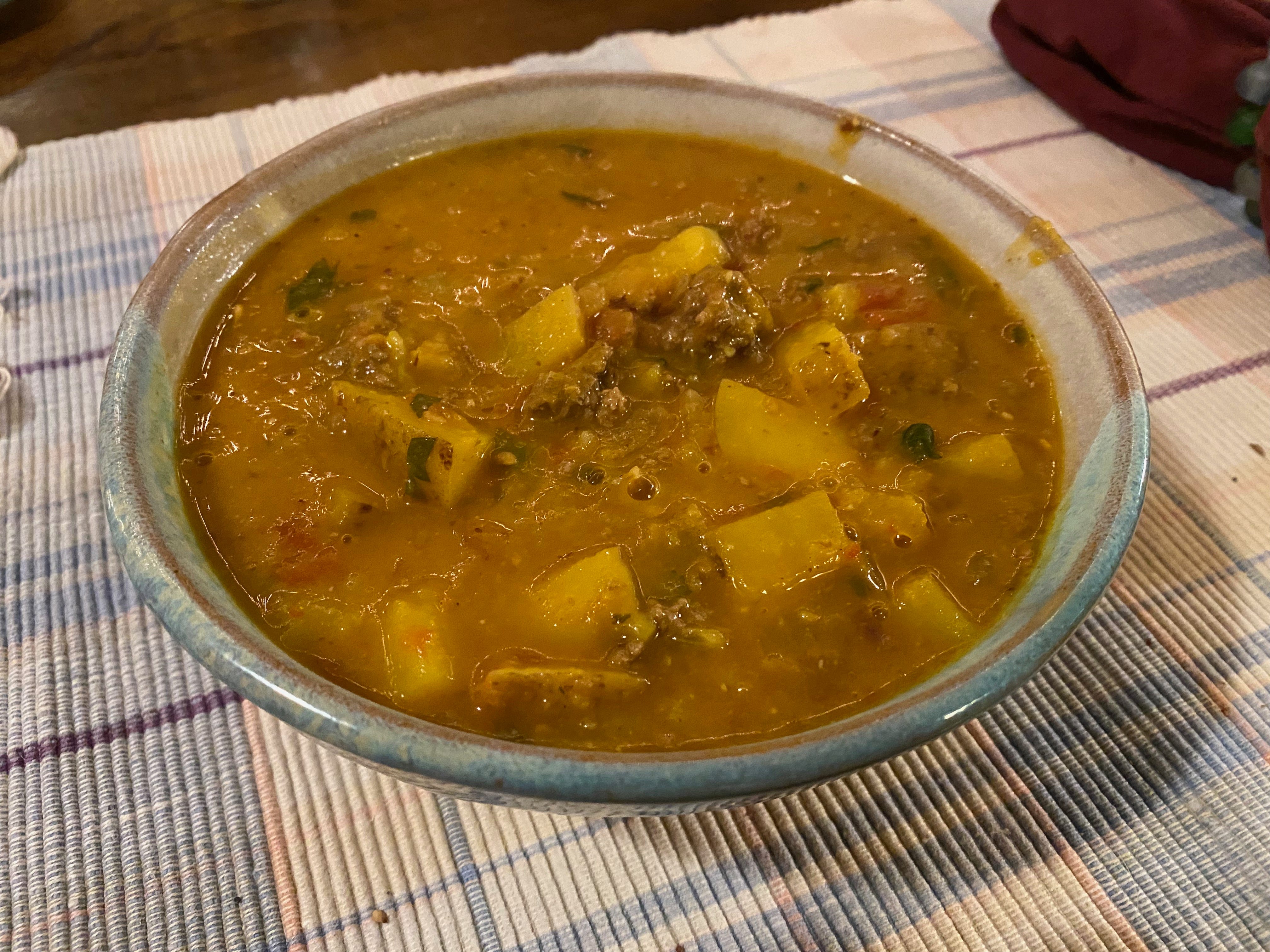 A ceramic bowl of thick white bean stew on a woven placemat.