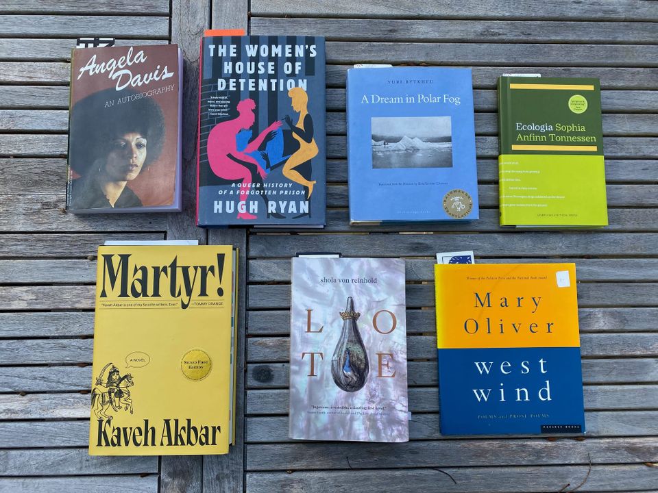 The seven listed books spread out on a porch table.