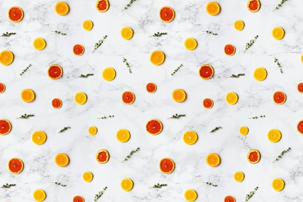 Colorful citrus slices arranged in a flat lay pattern on a marble surface, ideal for backgrounds.