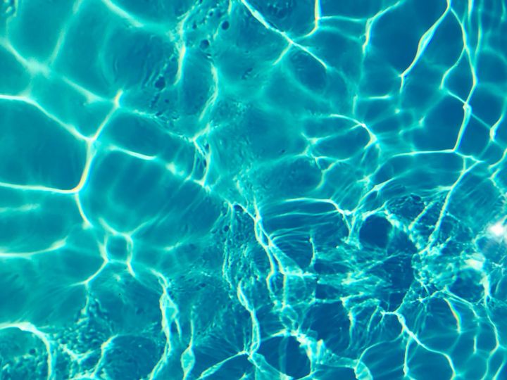 Bright turquoise water surface in sunlight, capturing shimmering patterns and reflections.