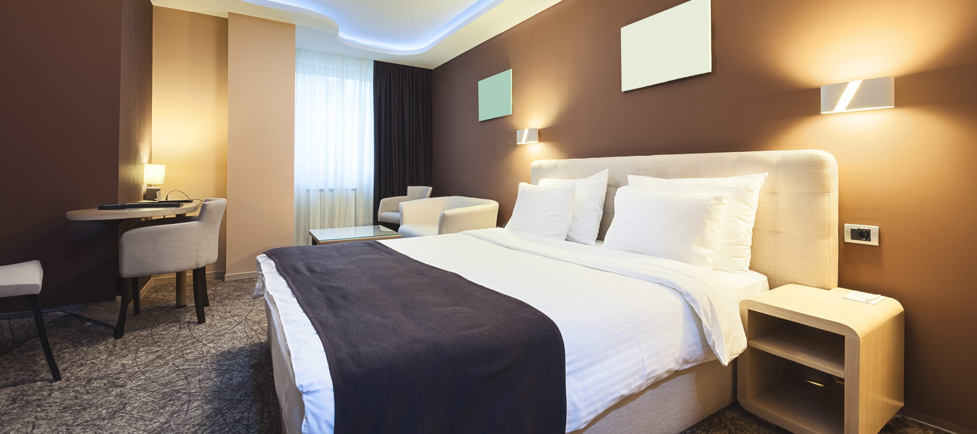 Inside a hotel room with one bed, side tables, and chairs. 