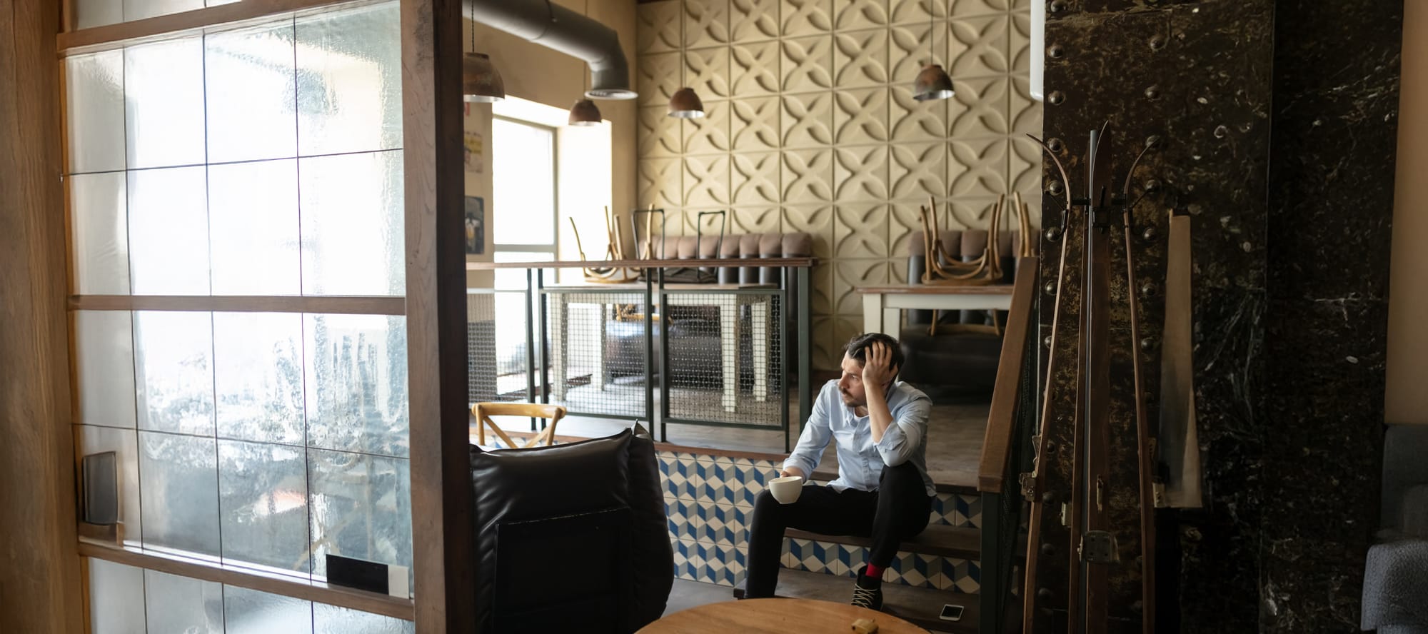 Small restaurant/cafe closed with owner drinking from a coffee mug and sitting on the steps.