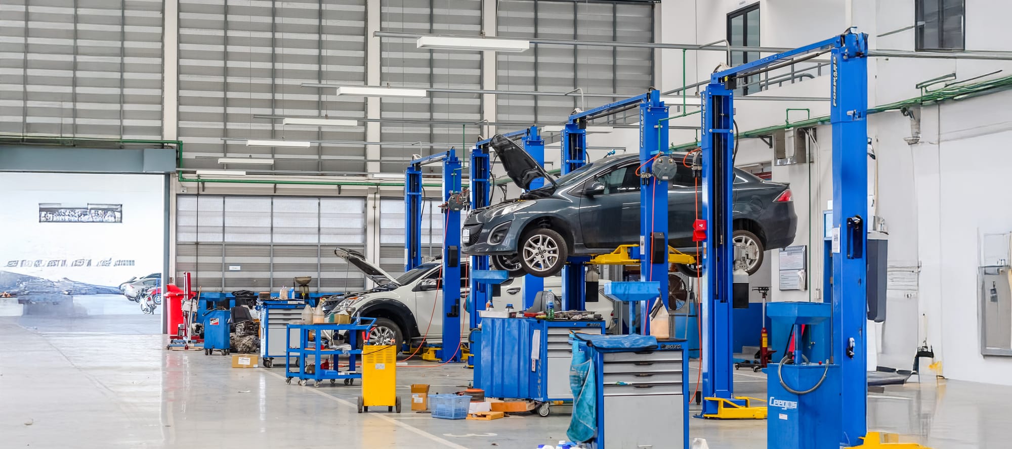 Car in blue lifting equipment in the garage being repaired.
