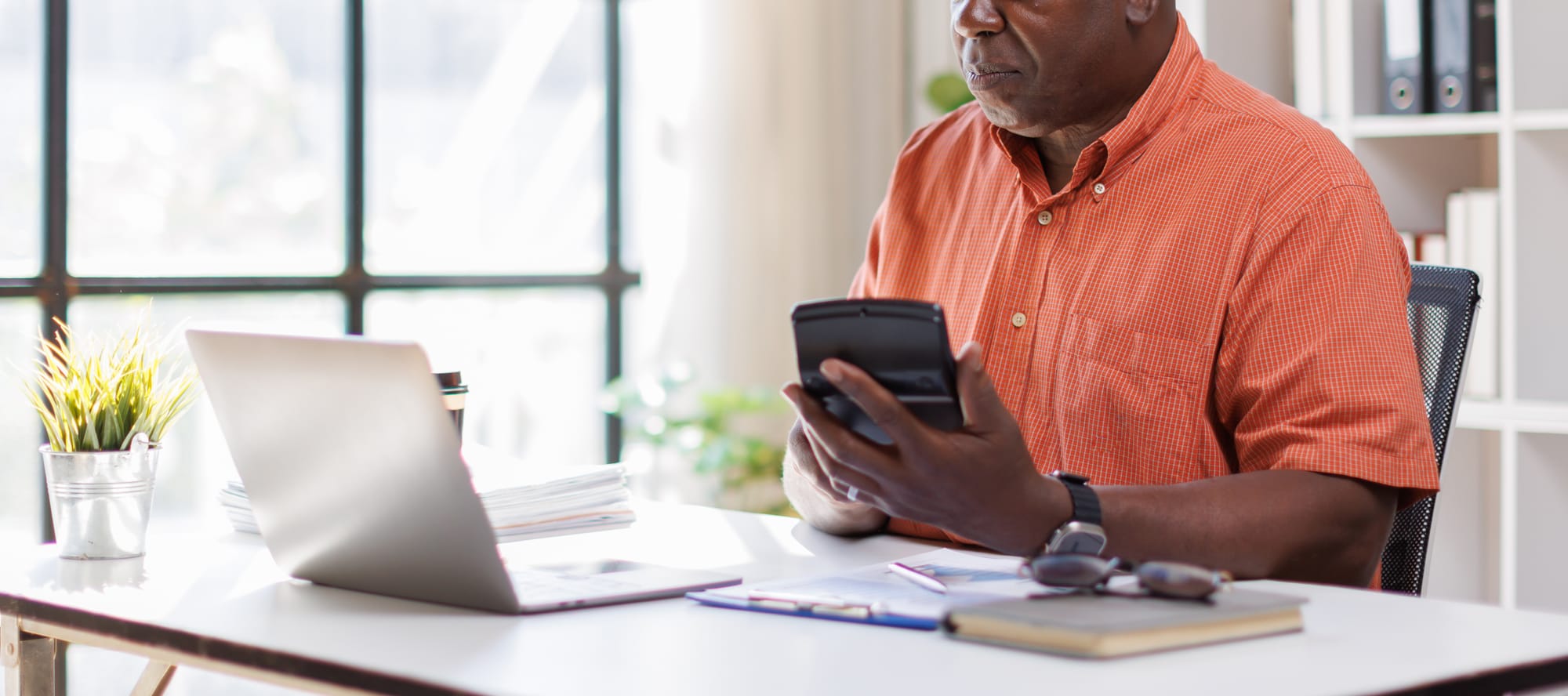 man working at office, using calculator to calculate costs on laptop. How does a Buyer's Premium work?