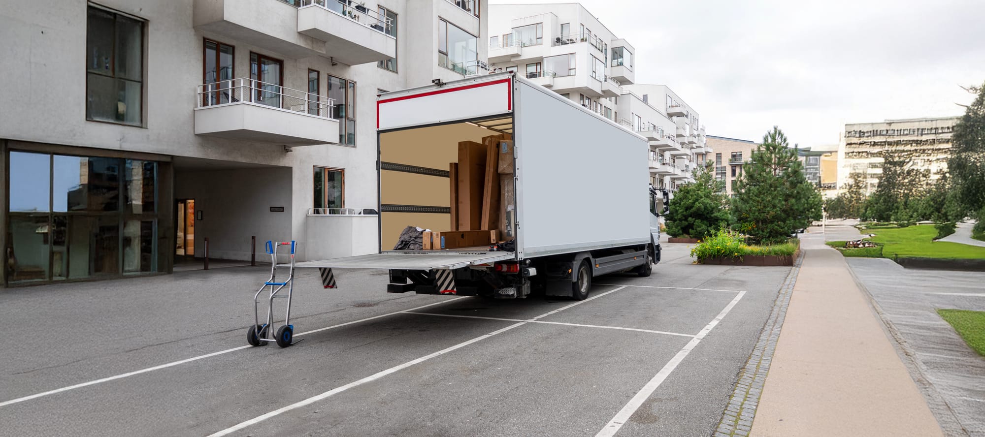 White box truck with tailgate open in front of white buildings. equipment auction pickup day / online auction pickup guide