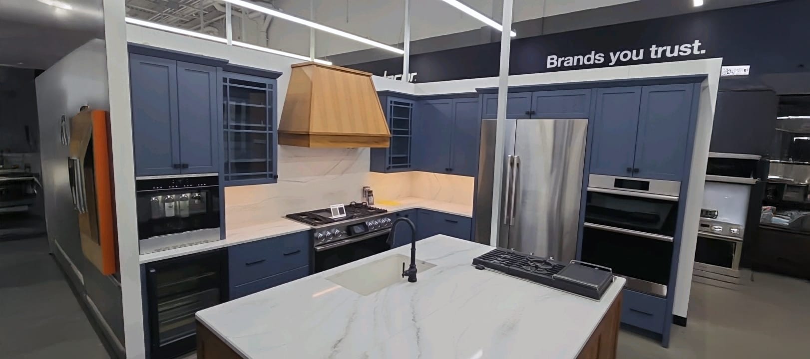 Display kitchen with blue cupboards, stainless steel appliances, and whit countertops. Home Depot Design Center