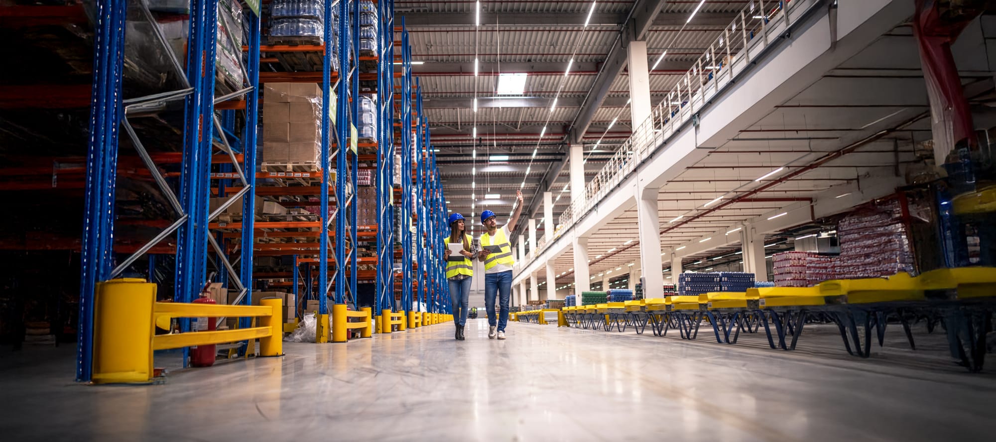 Distribution warehouse interior with two people walking through looking at equipment and checkboard