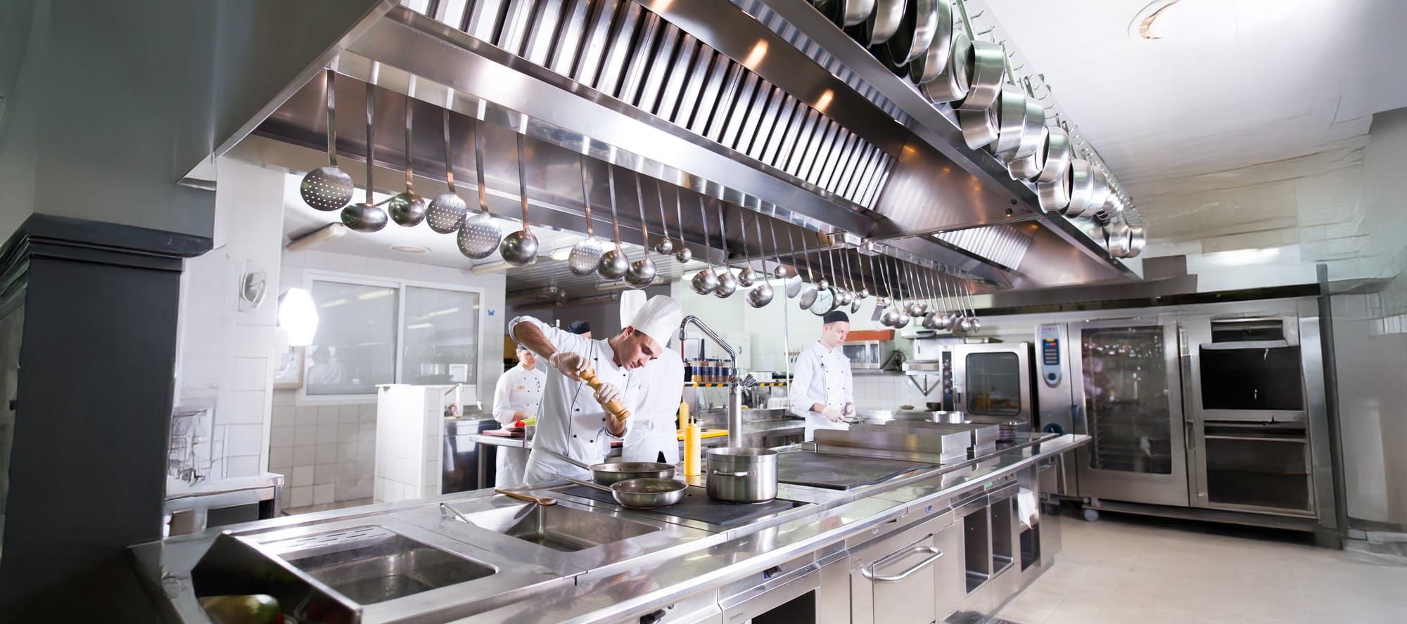 kitchen of the restaurant featuring stainless steel commercial kitchen equipment and three chefs