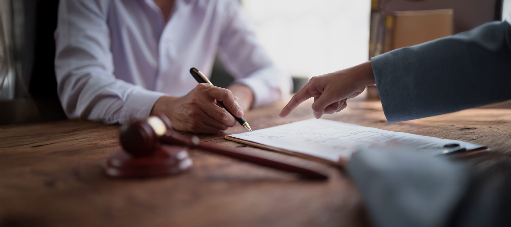 Client's hand signing a document with a pen 