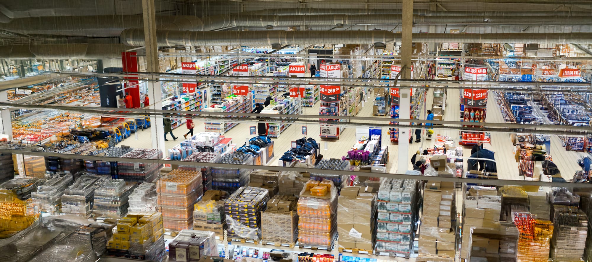 Wide view of a big box retail/supermarket store with front of house shelving and back of house pallets.