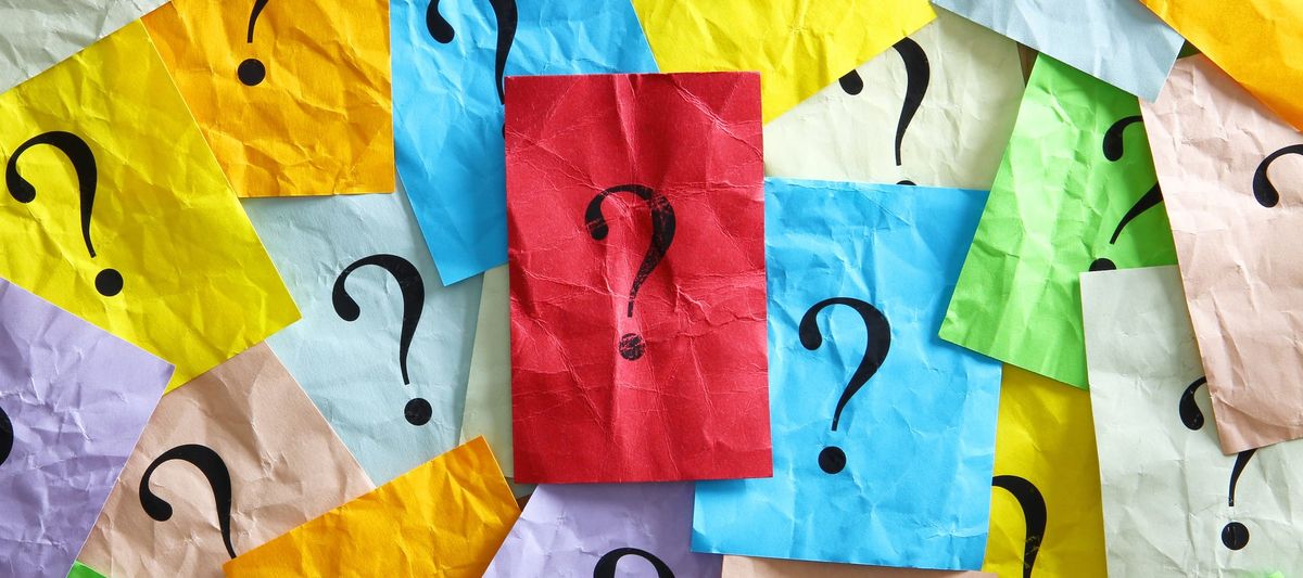 Multiple pieces of colored paper with question marks on them.