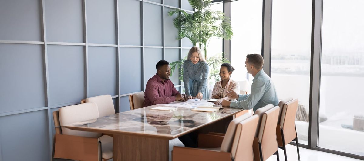 Group of professionals discussing strategy, working collaboratively on project gathered together in modern conference room.