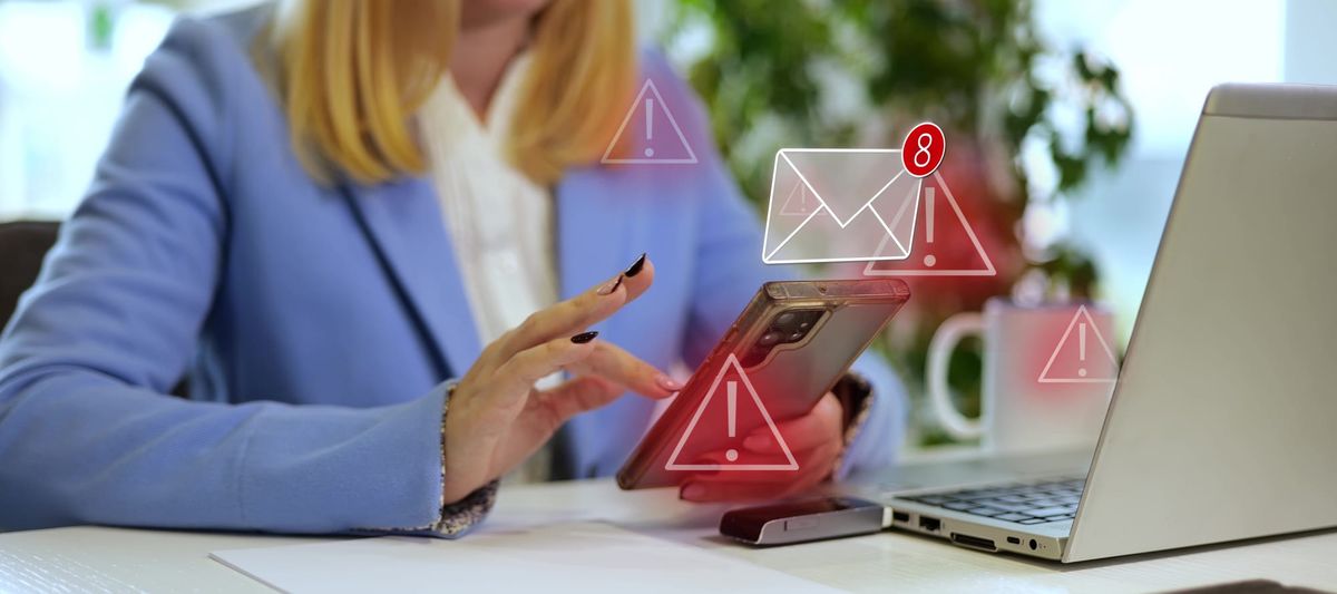 Woman in blue suit jacket experiences technology issues on her phone and computer.