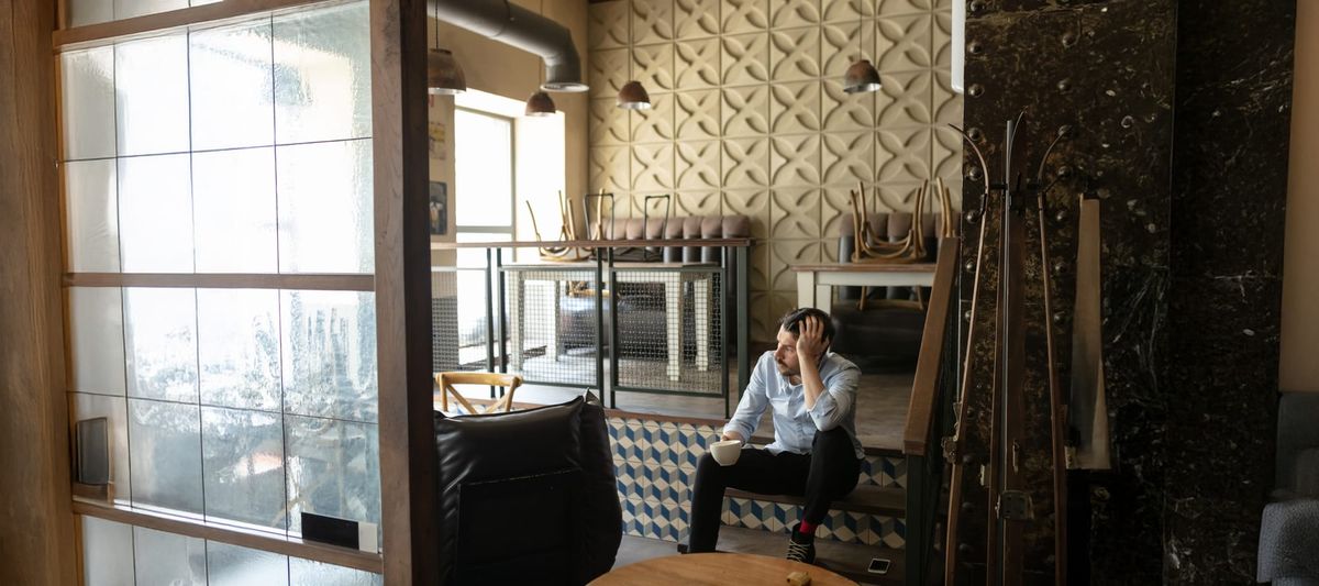 Small restaurant/cafe closed with owner drinking from a coffee mug and sitting on the steps.