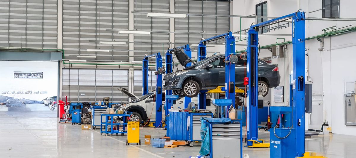 Car in blue lifting equipment in the garage being repaired.