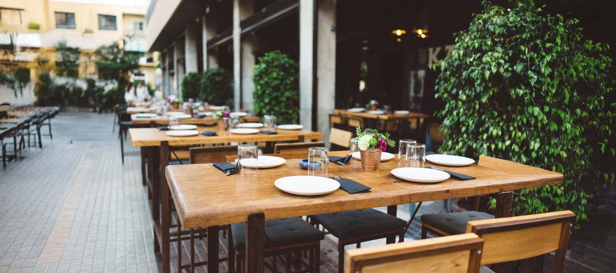 Restaurant patio with plants, dining tables and plates. Used Restaurant Equipment