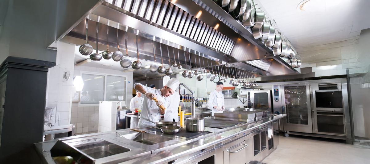 kitchen of the restaurant featuring stainless steel commercial kitchen equipment and three chefs