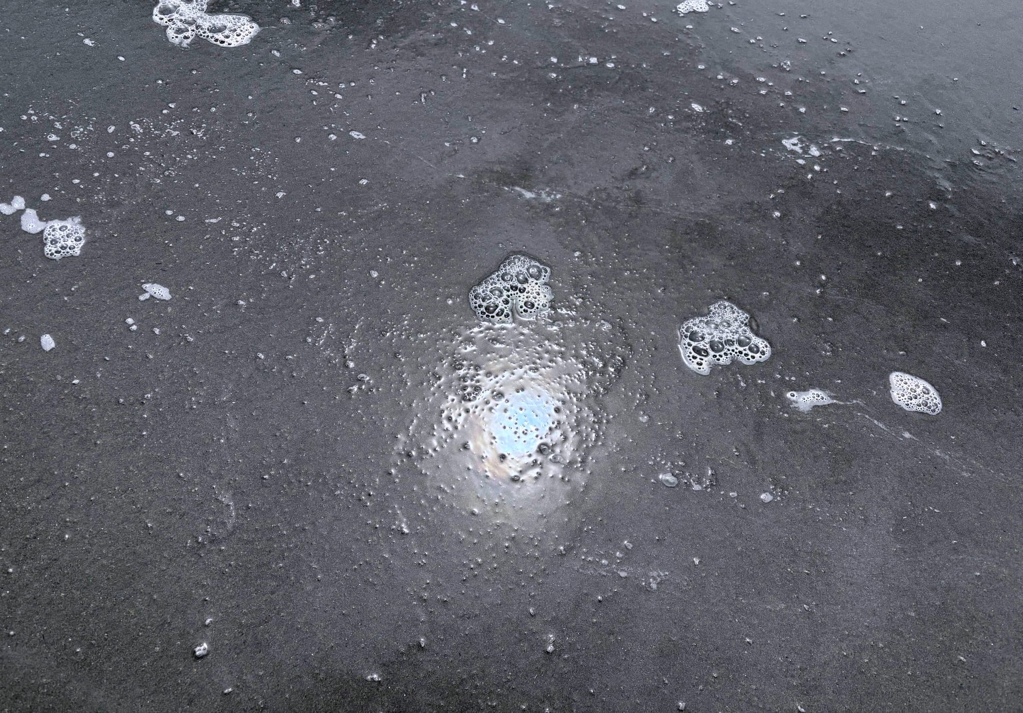 Photo of sun in wet sand, looking like a shiny, pale, bluish portal.