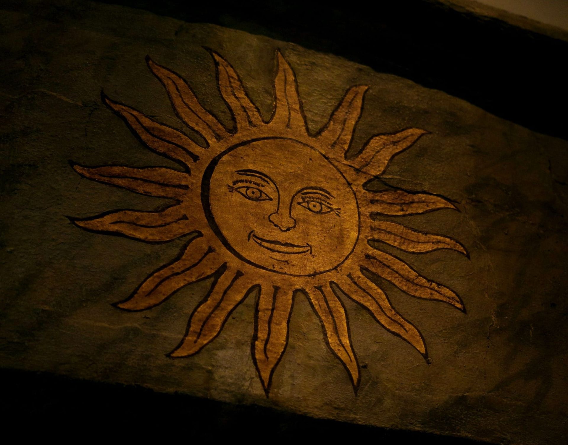 Image of illustration of sun with smiling face painted on wood.