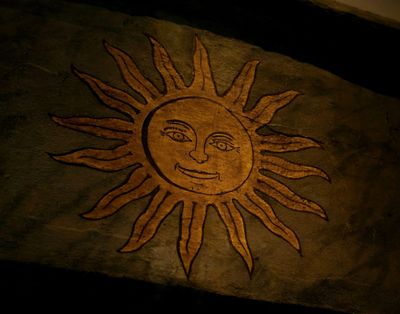 Image of illustration of sun with smiling face painted on wood.