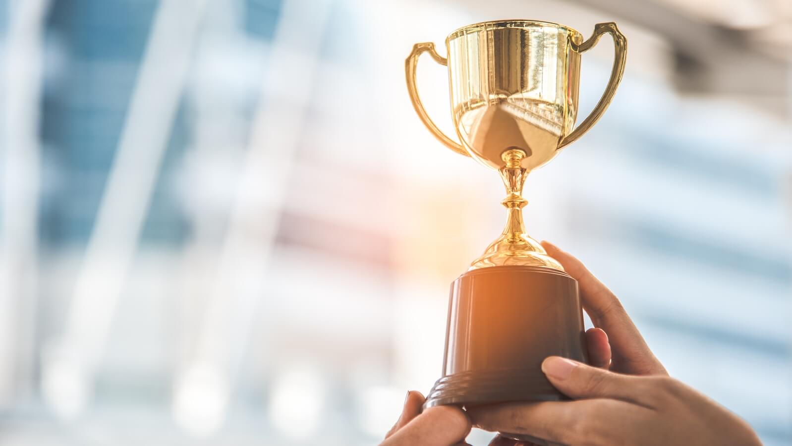 Hands holding a trophy cup: finding winning stocks