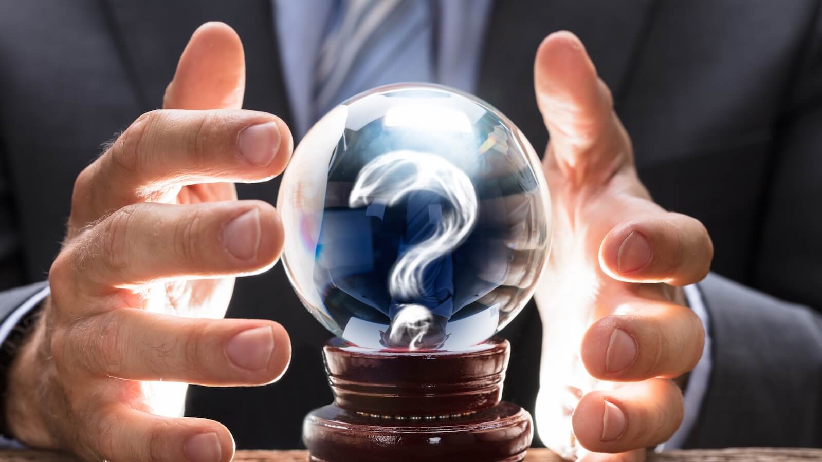Man's hands around a crystal ball that has a question mark