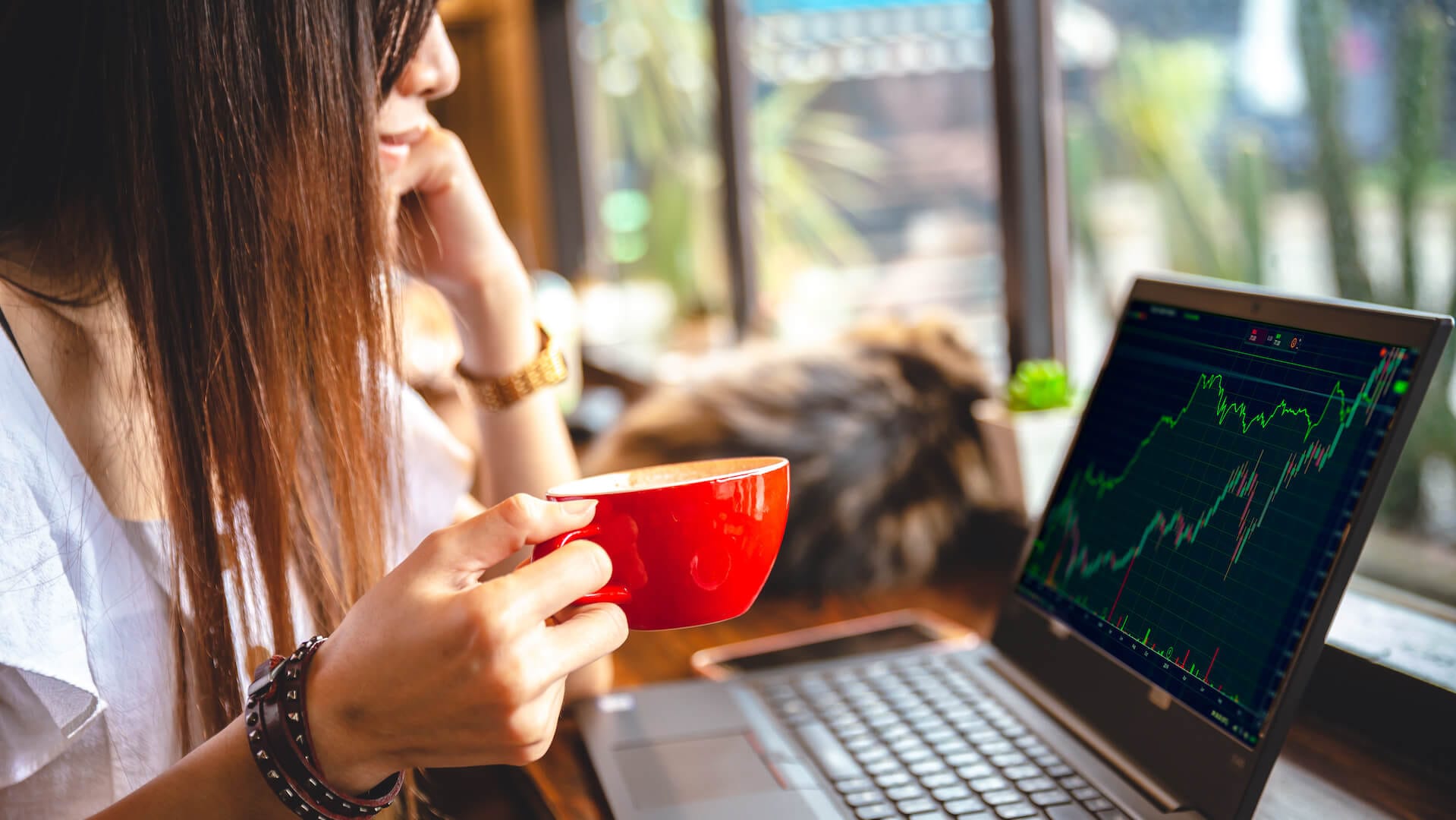 Lady in coffee shop watching charts on laptop