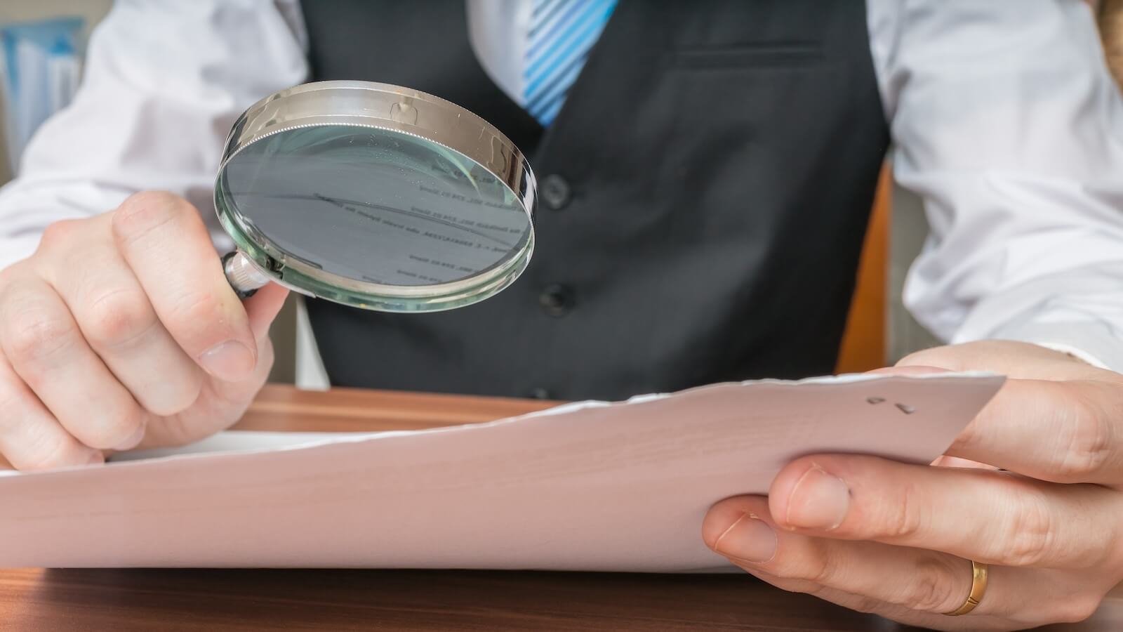 Person looking at document with magnifying glass