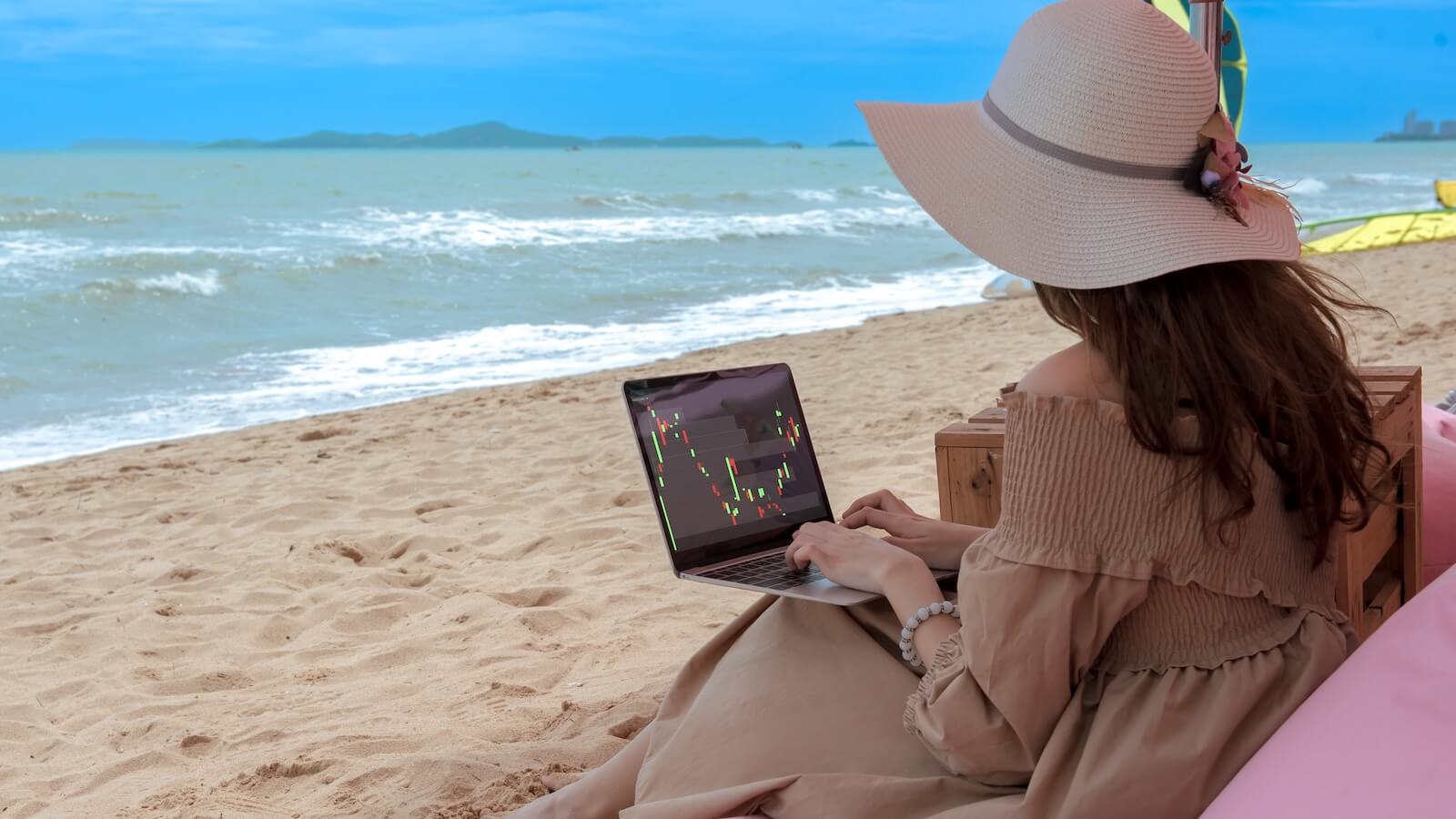 Woman on beach with laptop analyzing candlestick stock charts: Summer stock market setup