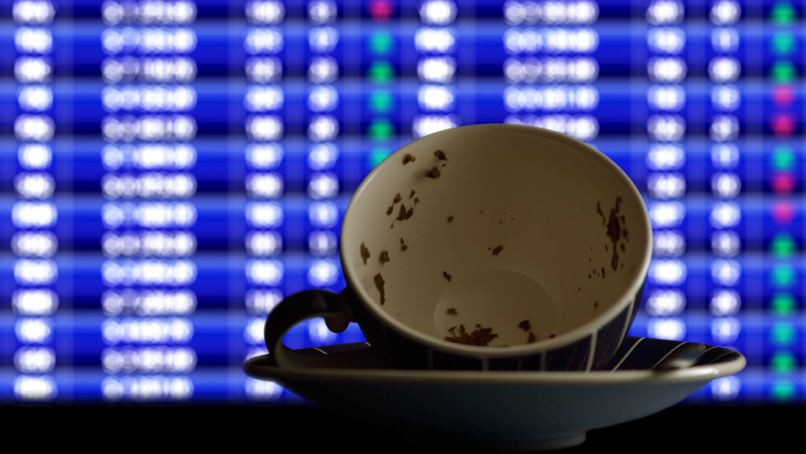 Cup with tea leaves in front of trading screen