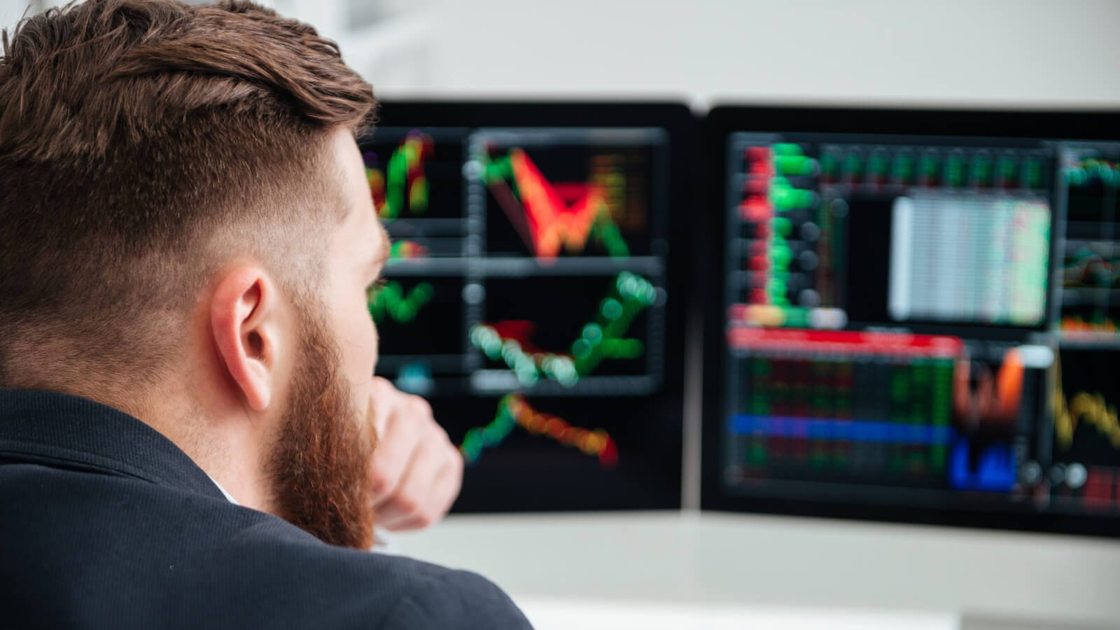 Man watching charts on monitor: Stock market at highs