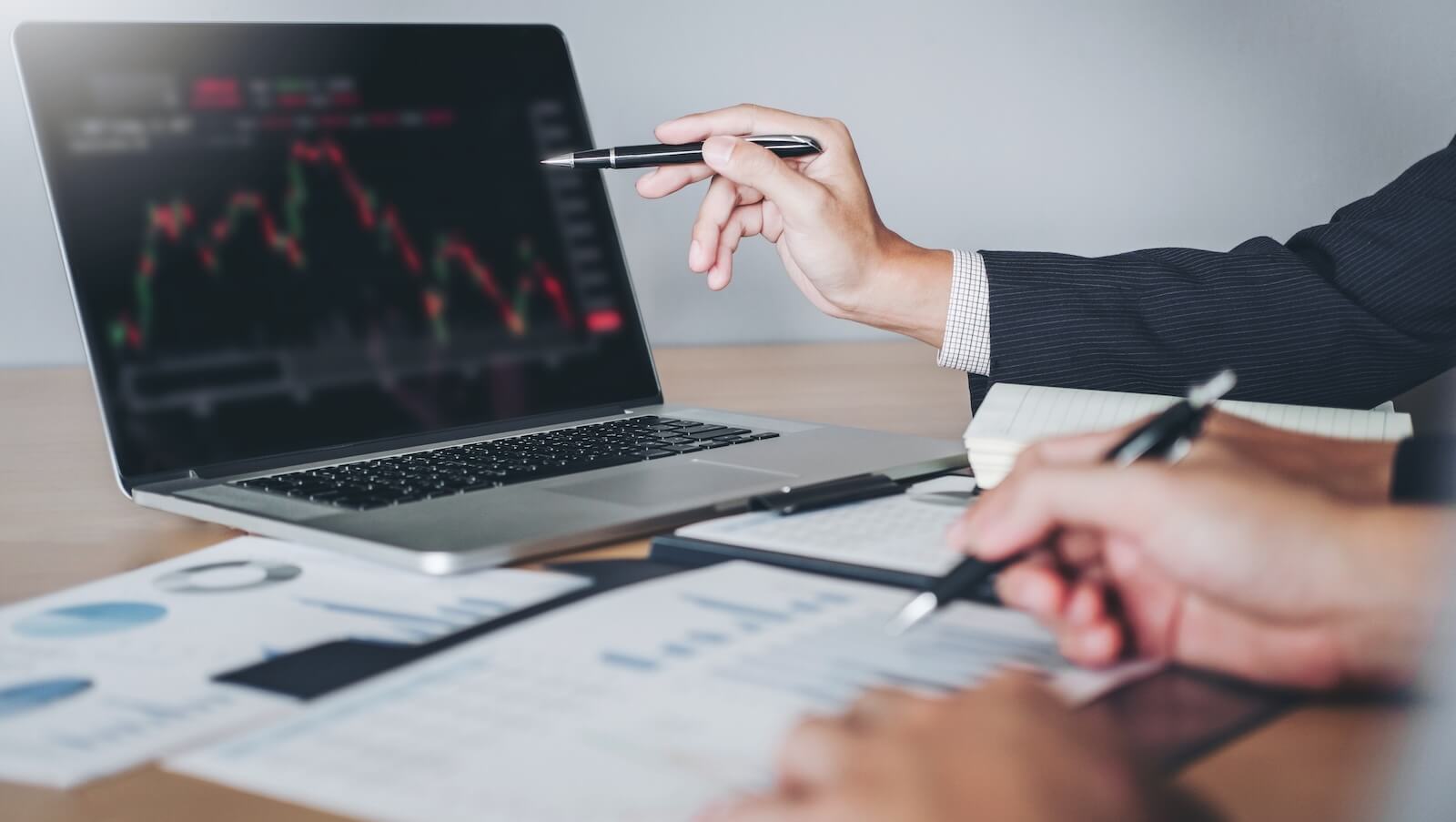 Two people analyzing charts on laptop: MACD or RSI