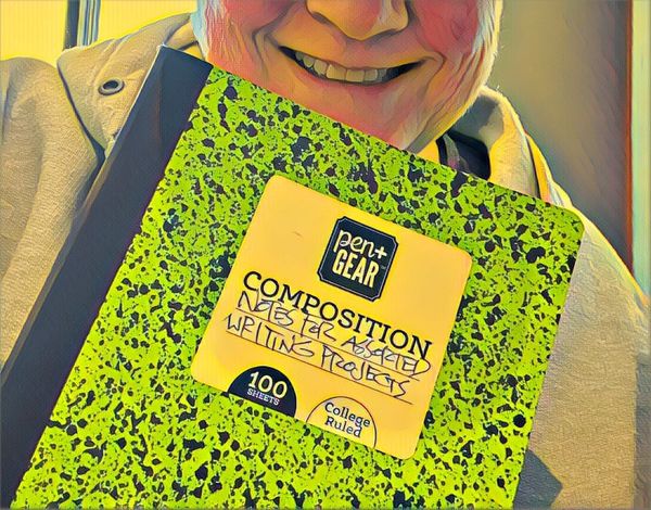 The bottom half of the author’s face, with a composition book held up to it