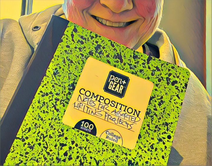 The bottom half of the author’s face, with a composition book held up to it
