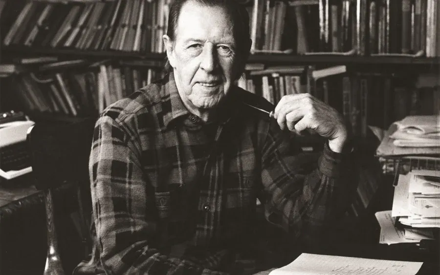 Scholar Raymond Williams wearing a checked shirt and holding a pipe.