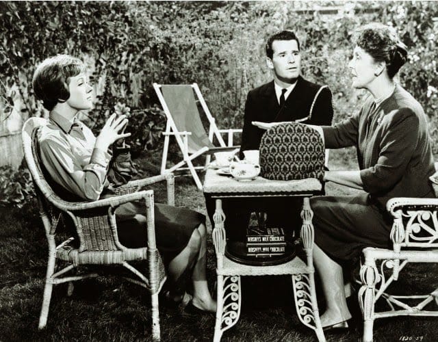 A still from The Americanization of Emily with Charlie Madison (James Garner), Emily Barham (Julie Andrews), and her mother (Joyce Grenfell) sitting outdoors at a table, having tea.l
