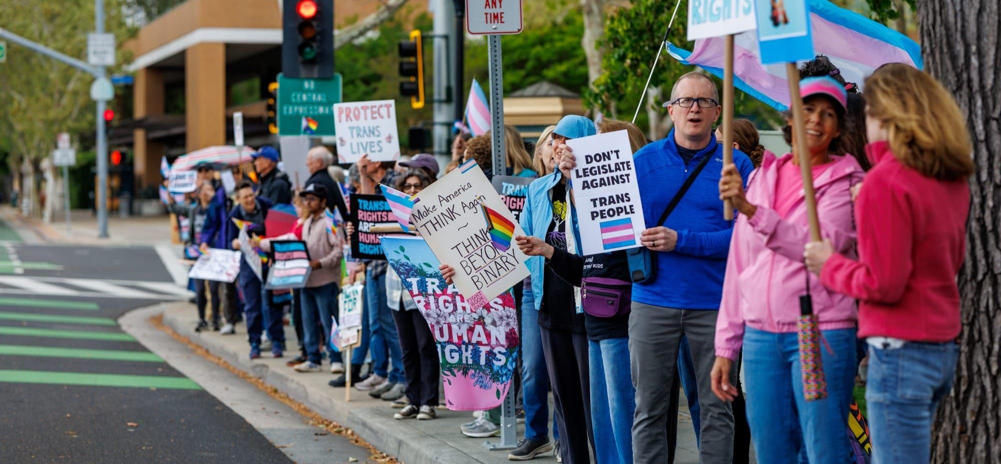Ordinary folks lined up on a street corner protesting in favor of transgender rights