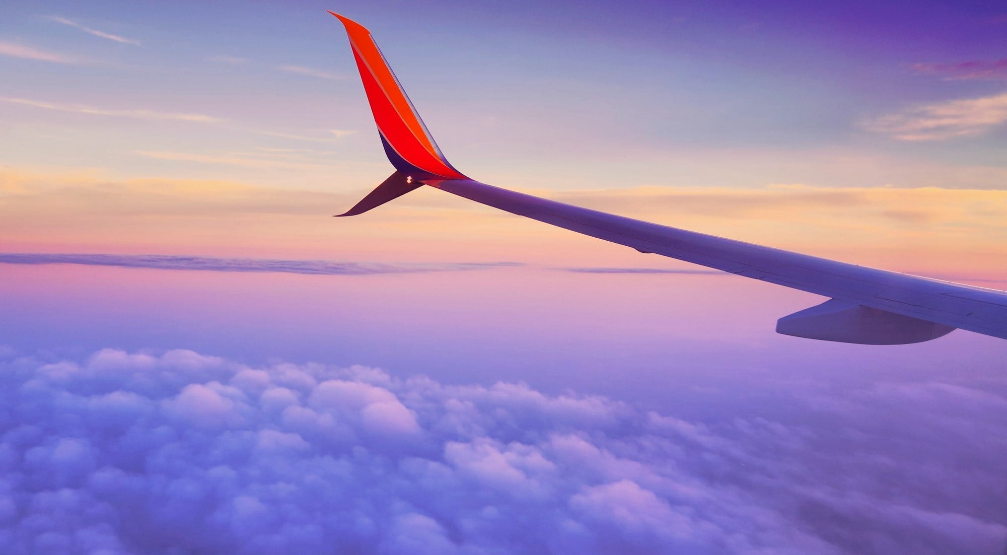 person in a plane flying at high altitude taking photo of left airplane wing during daytime