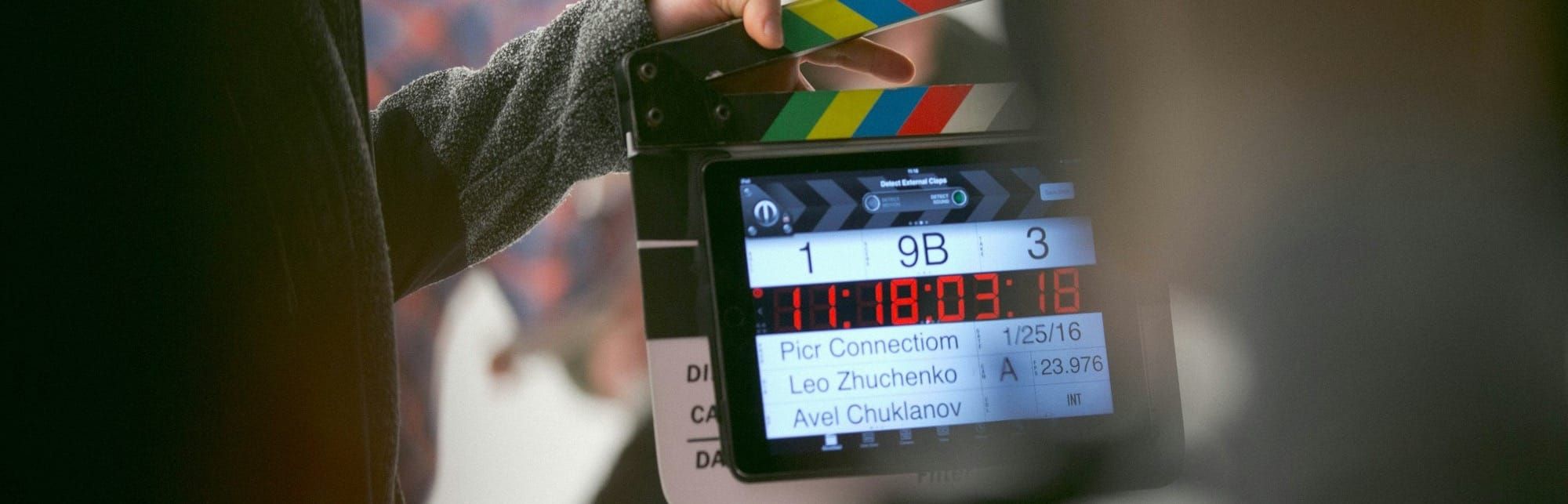 Two people on a film set with a film clapper in the foreground.